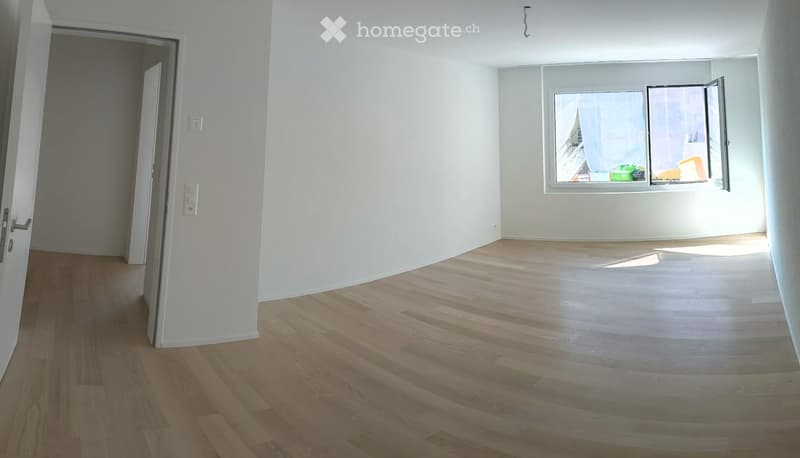 Empty room with light wooden flooring, white walls, and a large window with an open door leading to another space.