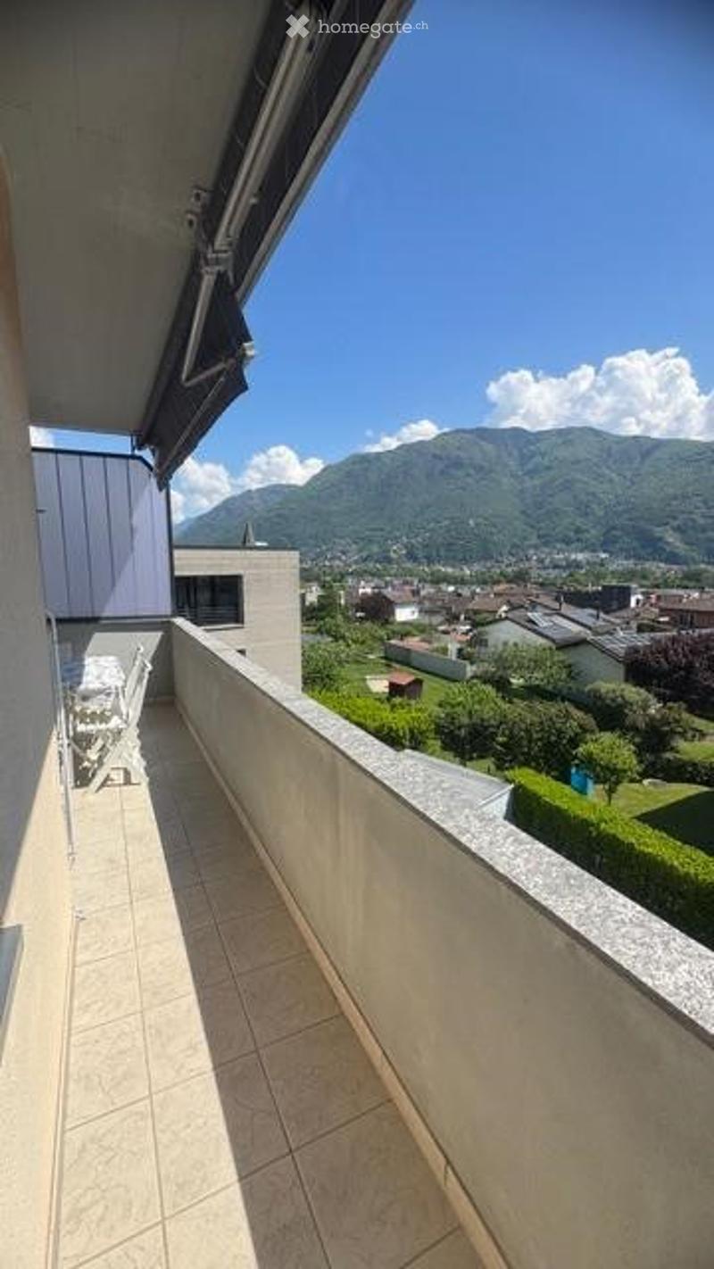 Balcony with tiled floor, overlooking a scenic mountain view and a town below.