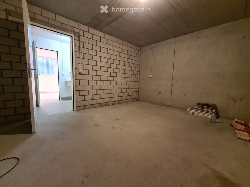Empty room with bare concrete walls and floor, featuring a doorway leading to another space.