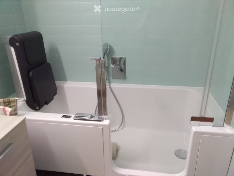 Modern bathroom with a white bathtub, chrome faucet, towel on the side, and a mirror above the sink.