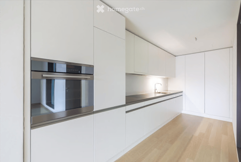 Modern, minimalist kitchen with white cabinetry, built-in oven, and a sleek sink with a modern faucet.