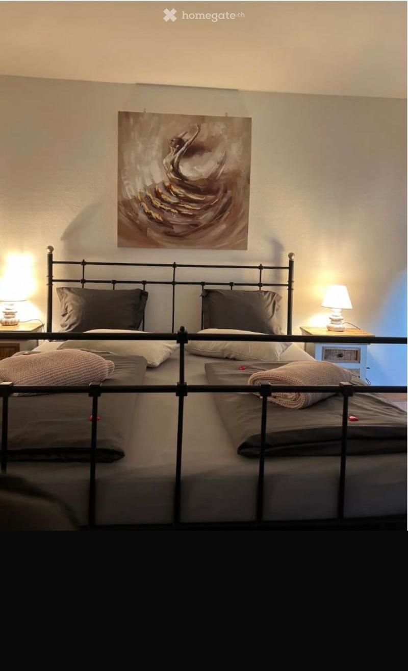 Cozy bedroom with a double bed, nightstands, lamps, and a decorative painting on the wall.