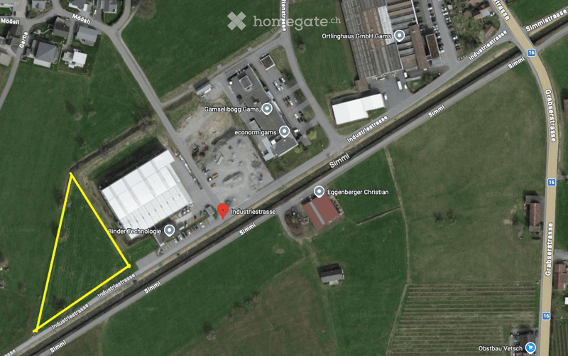 Aerial view of an area with fields, roads, buildings, and a marked plot of land.