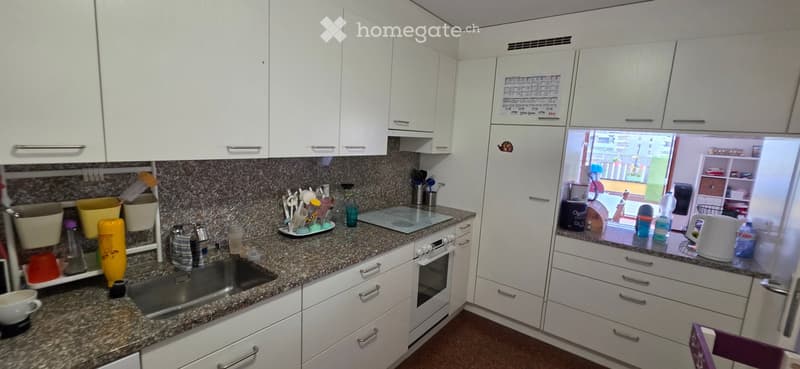 Modern kitchen with white cabinets, granite countertops, stainless steel sink, and various kitchen utensils and appliances.