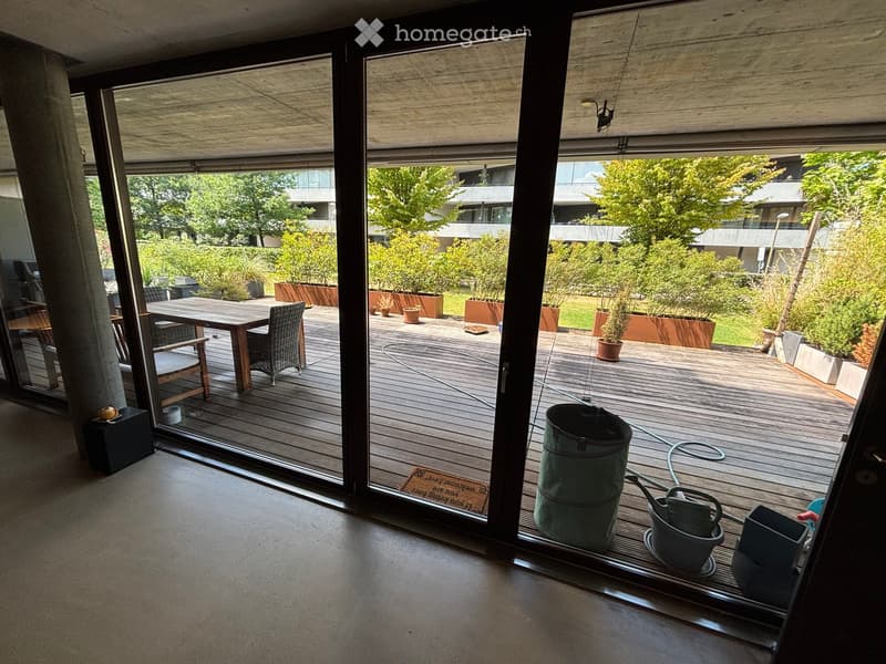 Balcony with wooden decking, outdoor furniture, potted plants, and gardening tools.