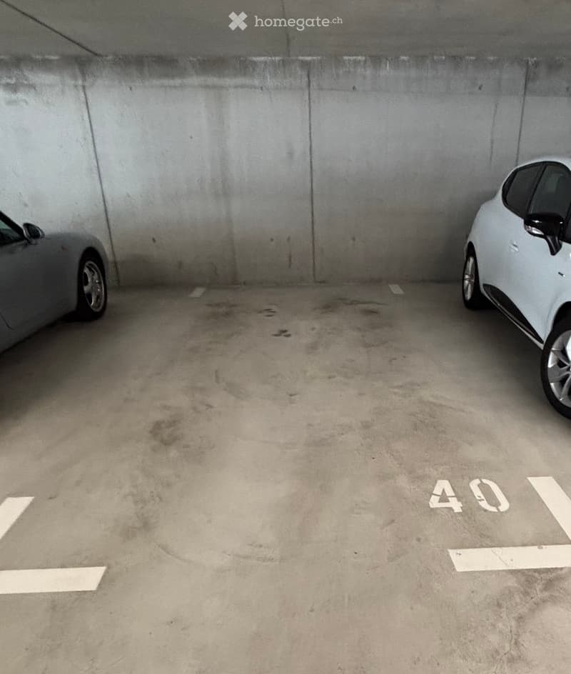 Underground parking space with two parked cars and marked parking spots.