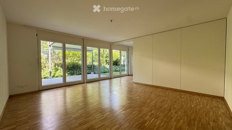 Empty room with wooden flooring and large sliding glass doors leading to an outdoor area.