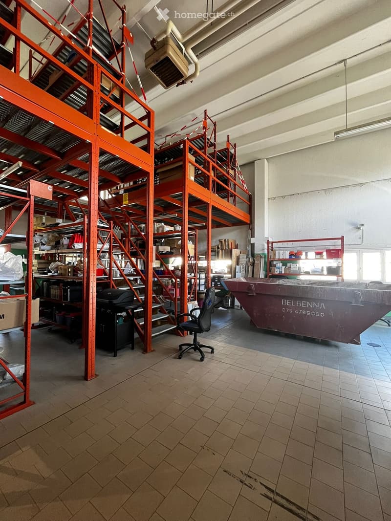 Large warehouse with metal shelving units, storage boxes, and a large dumpster.