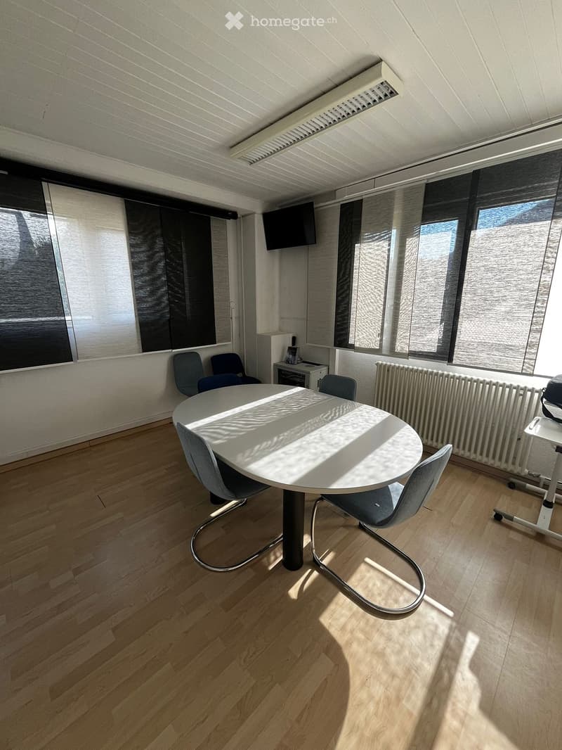 empty room with a round table, chairs, radiator, windows, and a television