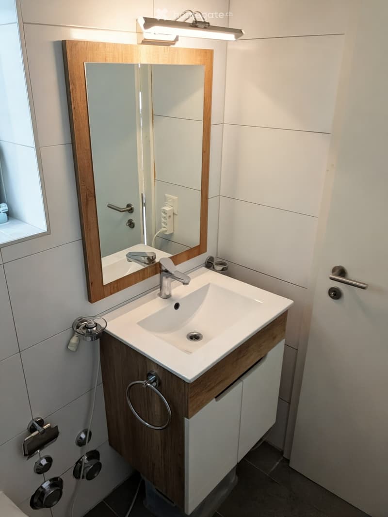 Modern bathroom with a white sink, chrome faucet, wooden-framed mirror, and built-in cabinetry.