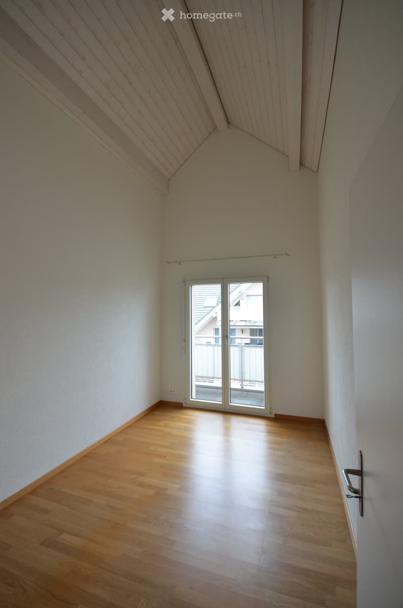 Empty room with wooden flooring, white walls, and a large sliding glass door leading to a balcony.
