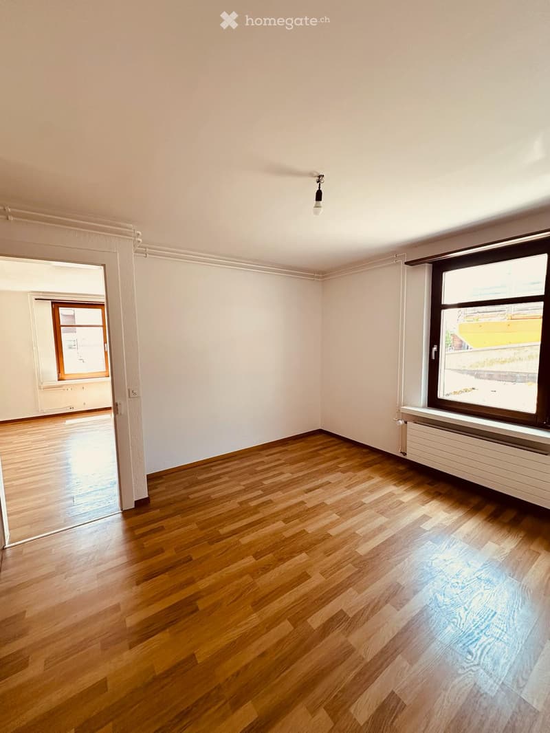 Empty room with wooden flooring, white walls, and large windows. No furniture or equipment present.