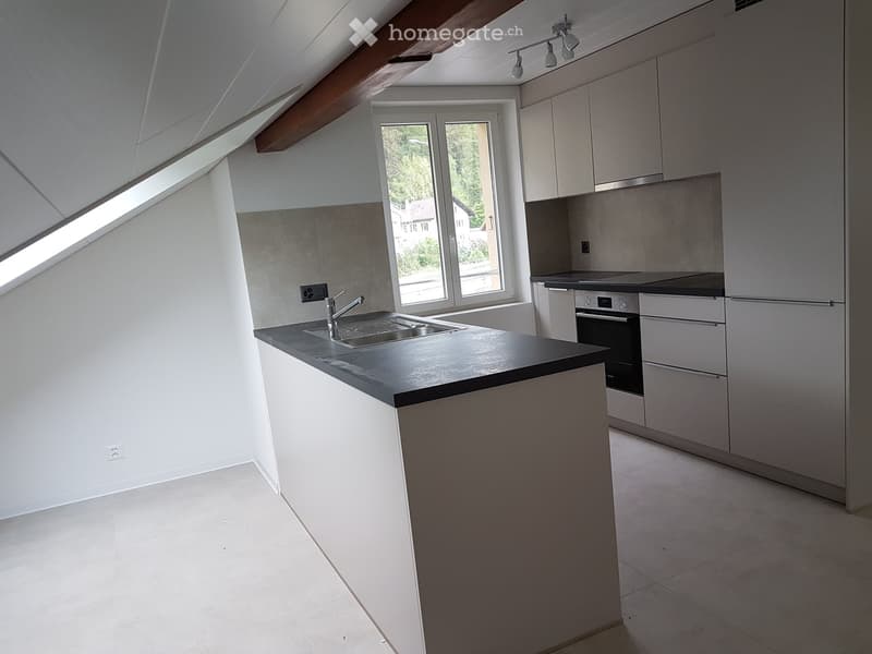 Modern kitchen with white cabinets, a central island, and a sink with a faucet. The space features large windows and a sleek, contemporary design.