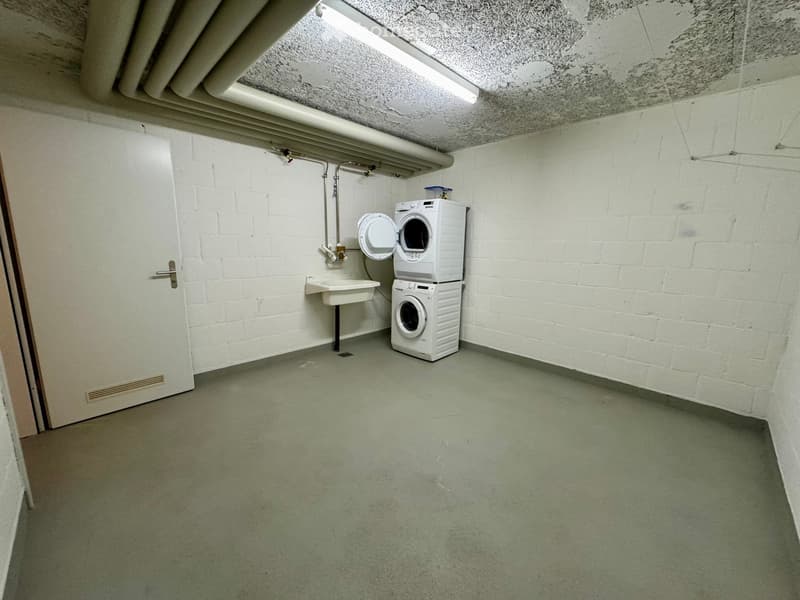 Laundry room with washing machine, dryer, sink, and white brick walls