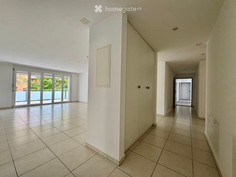 Empty room with sliding glass doors leading to a balcony, tiled floor, white walls, and built-in wardrobes.