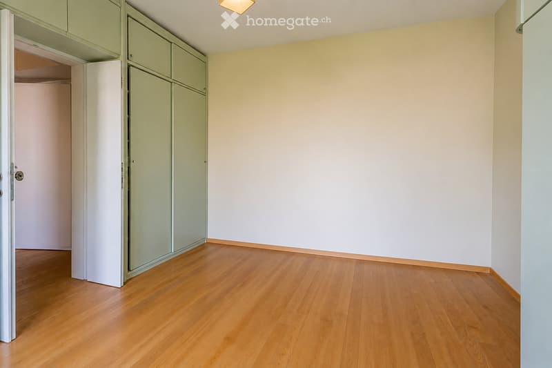 Empty room with light-colored walls, wooden flooring, and built-in closet units.