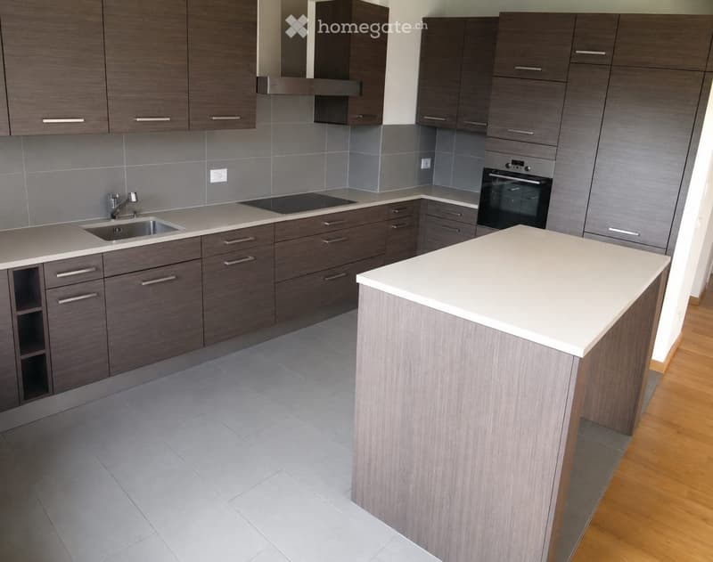 Modern kitchen with dark wood cabinets, white countertops, stainless steel sink, and built-in oven. Features an island with white countertop and grey base.