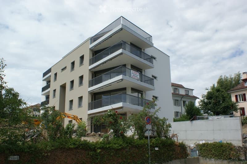 Modern multi-story apartment building with multiple balconies and contemporary design.