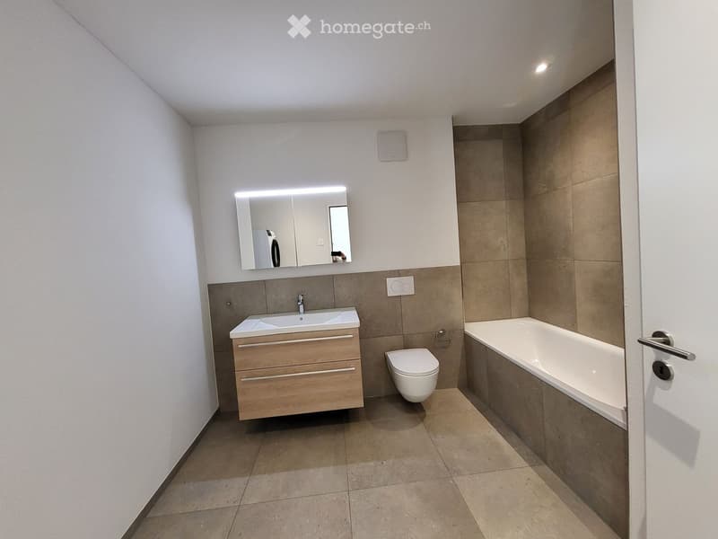 Modern bathroom with a double sink, mirror, toilet, bathtub, and a wooden cabinet.
