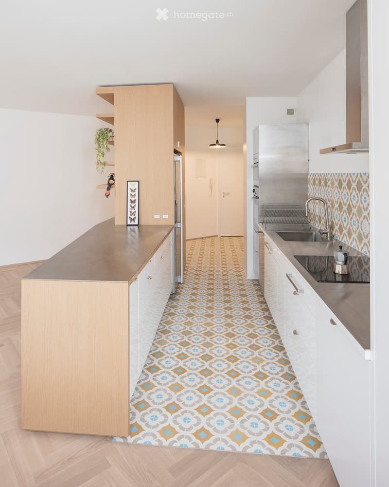Modern kitchen with wooden counter, stainless steel sink, and patterned tile floor.