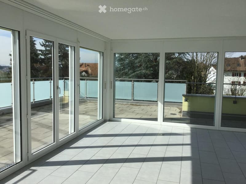 Empty room with large glass sliding doors leading to a balcony, tiled floor, and white walls.