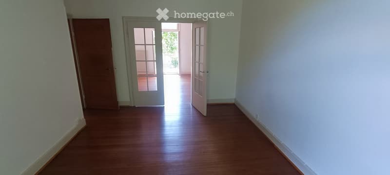 Empty hallway with wooden flooring, light blue walls, and a door leading to an outdoor area.