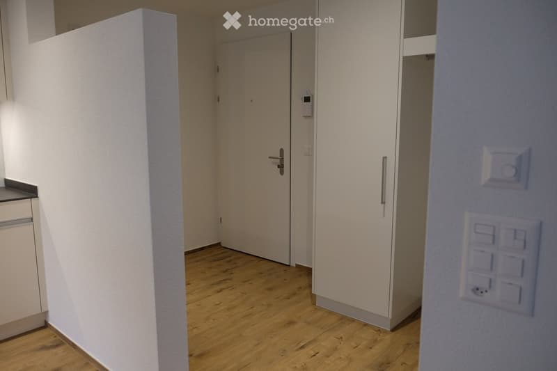 Empty room with wooden flooring, white walls, and a closed door leading to another space. No furniture or equipment is present.