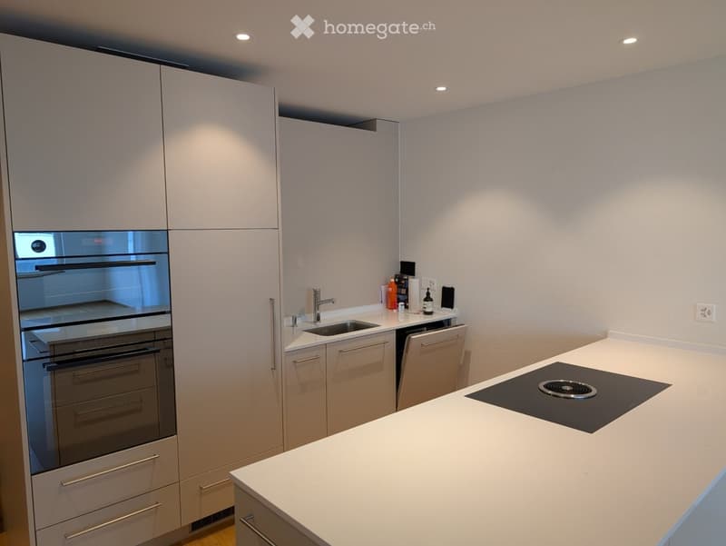 Modern kitchen with white cabinets, stainless steel appliances, and a white countertop.