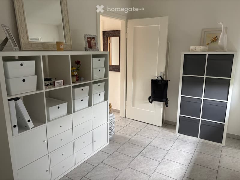 A clean, organized hallway with white storage units, a large mirror, and a door leading to another room.