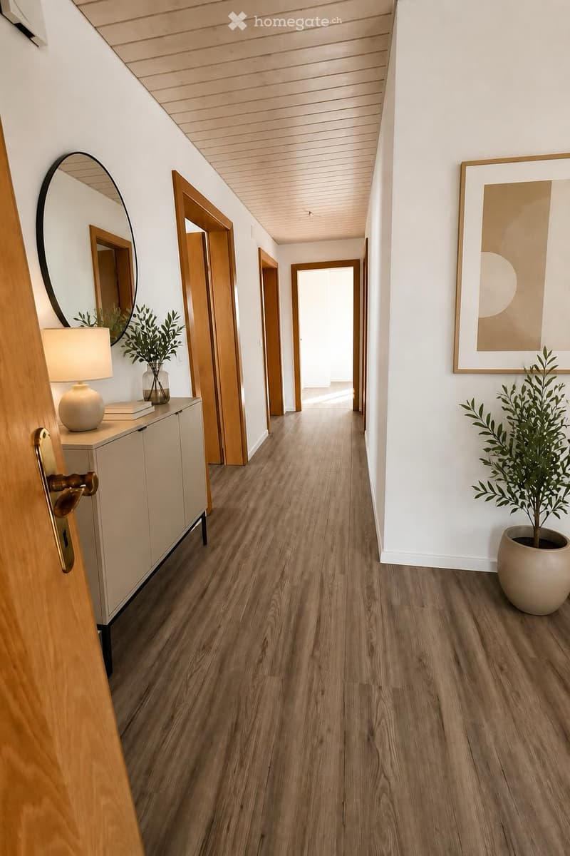 Modern hallway with wooden flooring, white walls, and several doors leading to different rooms. Features include a round mirror, a small table with a lamp, and a potted plant.