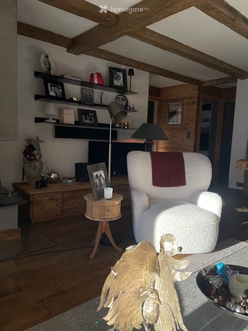 large white chair, wooden table, floor lamp, TV, picture frames on wooden shelf, wooden floor