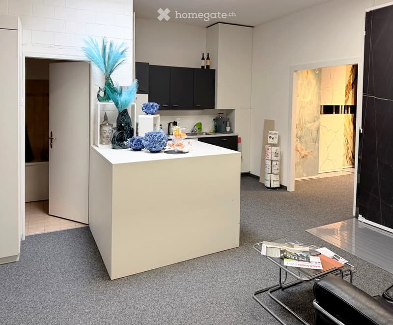 A modern, well-lit room with a kitchen island, a sofa, a coffee table, and various decorative items including vases and a faucet.