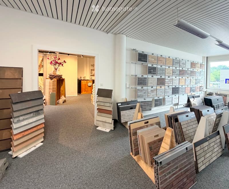 A showroom displaying various tile and wood samples, with neatly arranged stacks of tiles and wood samples on display, a cabinet with a vase of flowers, and a display of samples on a metal rack.