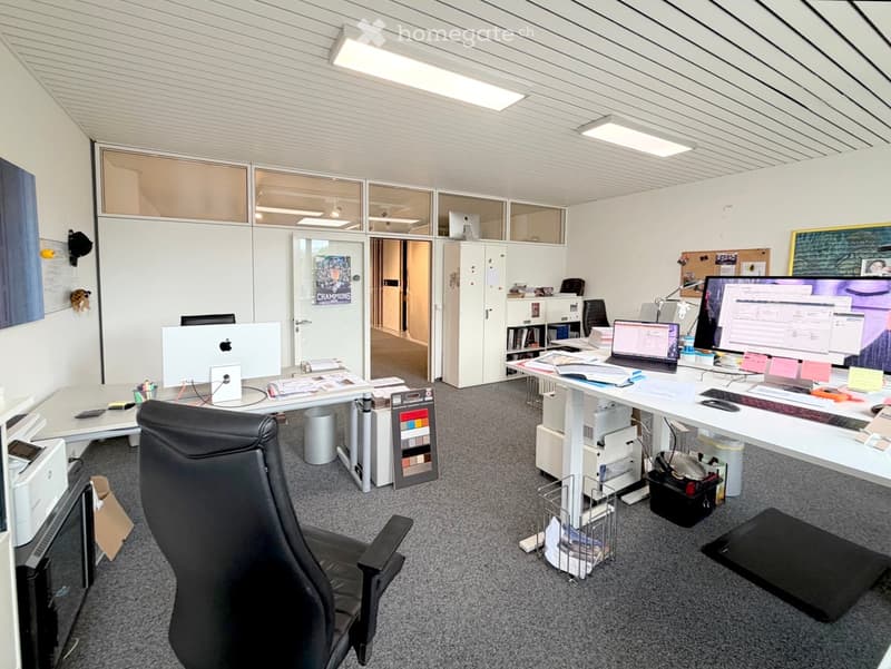 Office space with two desks, chairs, multiple computer screens, laptops, keyboards, and office supplies.
