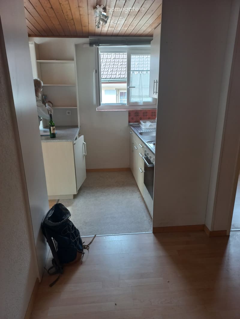 small kitchen with a window, counter with appliances, wooden floor, shelves