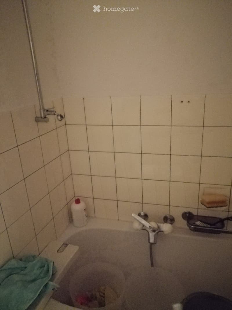 Bathtub with faucet, soap dish, and shower head on wall, tile walls and floor