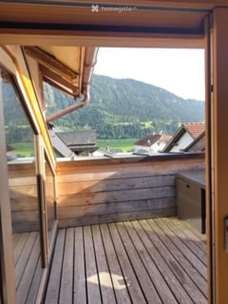 Wooden balcony with a scenic mountain view, featuring a wooden deck and open wooden frame.