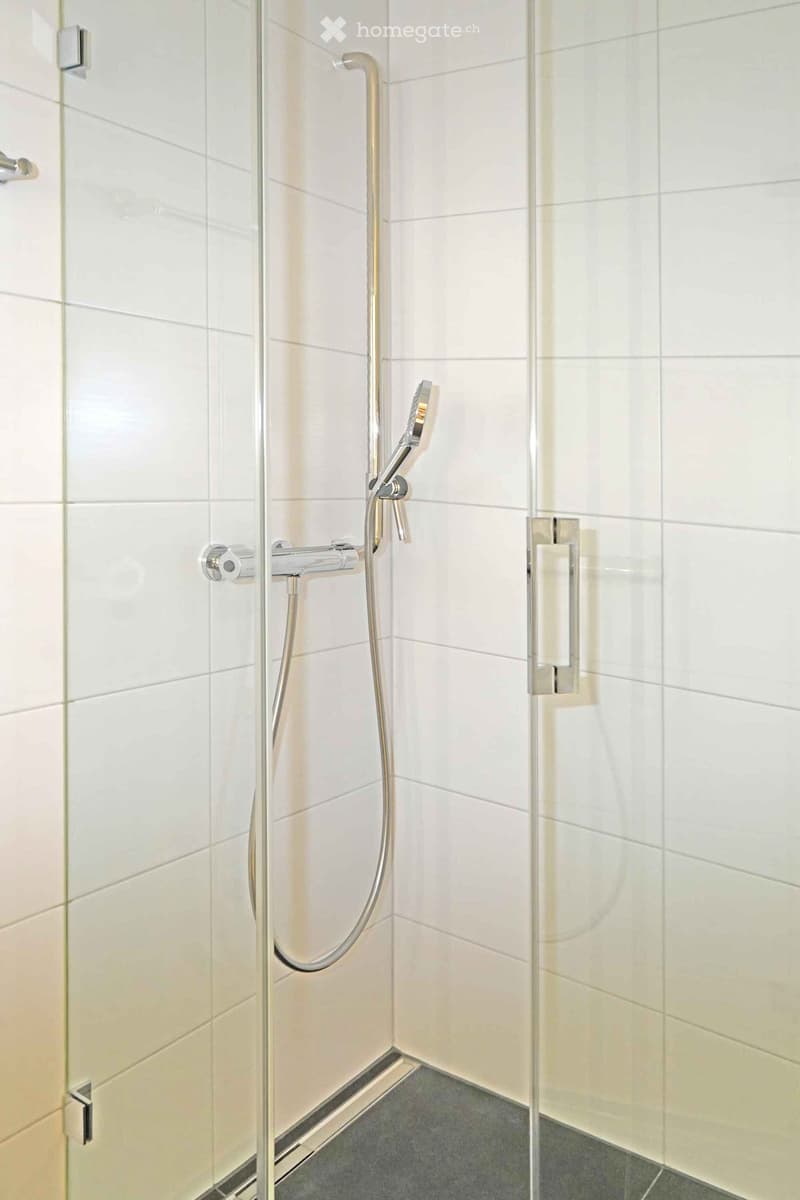 shower area with glass door, silver shower head, tiled walls, tiled floor