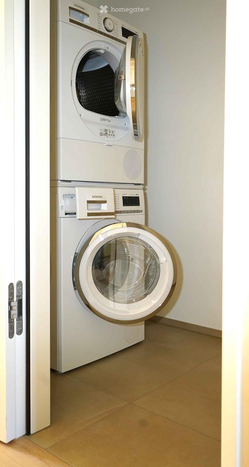 Stacked washing machine and dryer, tiled floor, white walls