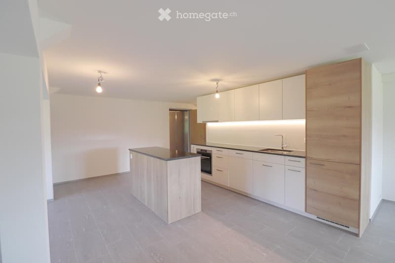Modern kitchen with light-colored cabinets, a central island, and built-in appliances including an oven and sink.