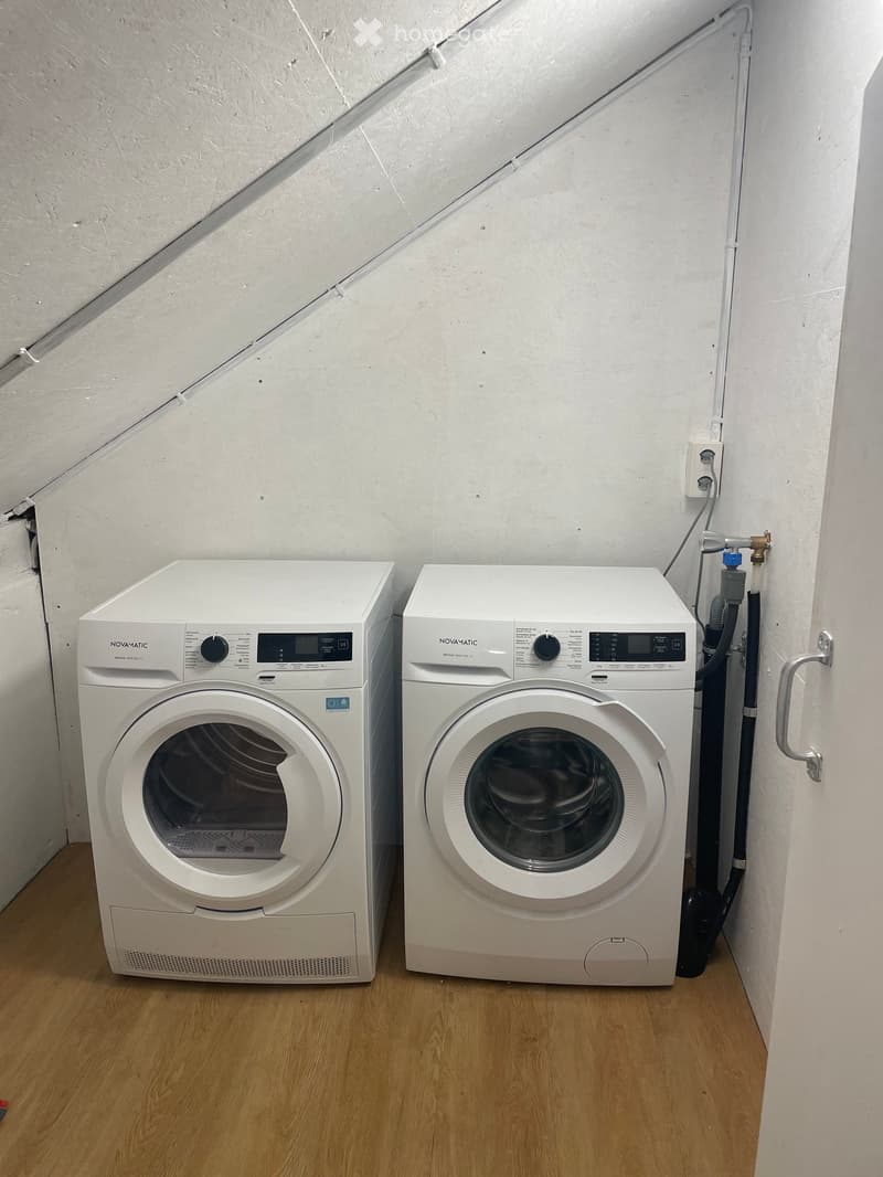 Bathroom. A small utility space with a washing machine and dryer, both white, placed side by side on a wooden floor.