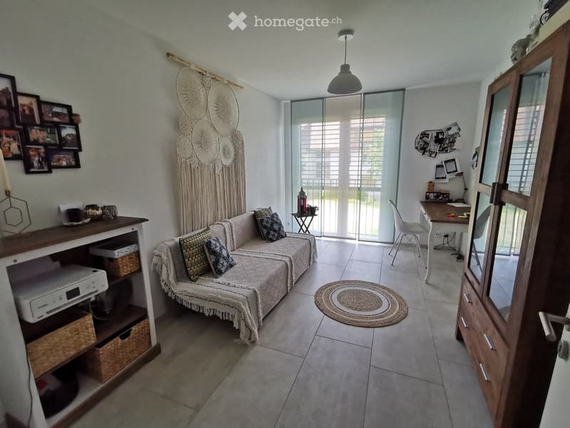 A cozy living room with a sofa, a small table, a chair, a cabinet, a lamp, a mirror, picture frames, a printer, and a rug.