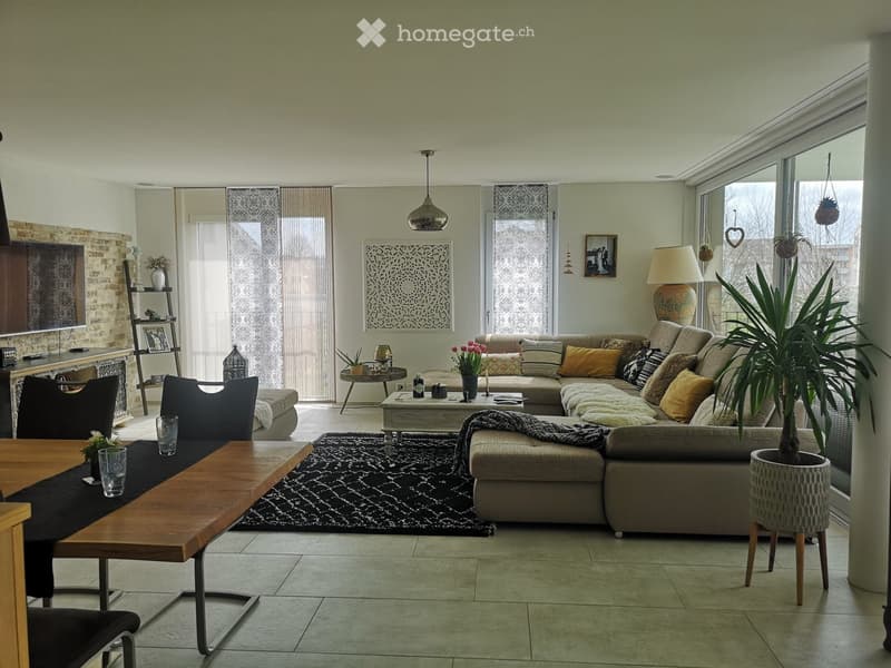 Modern living room with a large sectional sofa, coffee table, dining table, chairs, lamps, and decorative items.