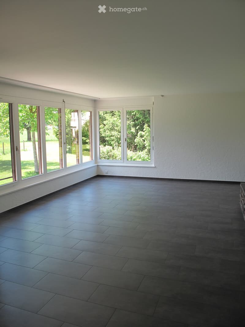Empty room with large windows and dark tiled flooring, no furniture or equipment.