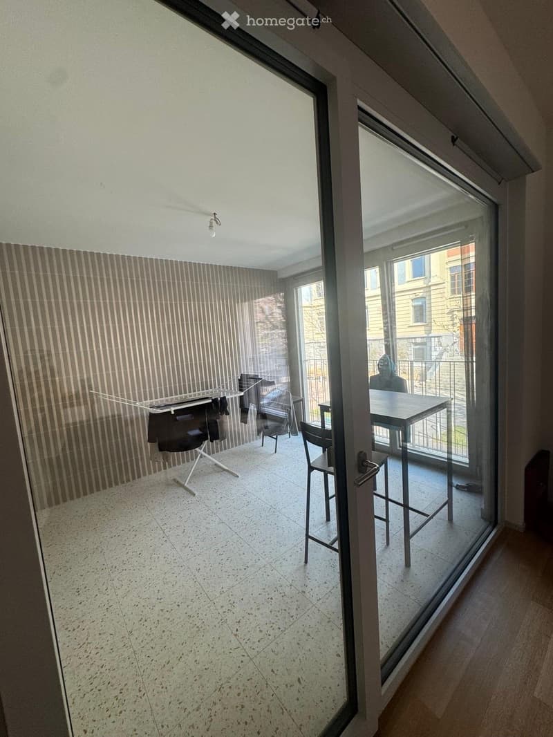 Balcony with a table and chairs, clothes drying rack, and a view of the city.