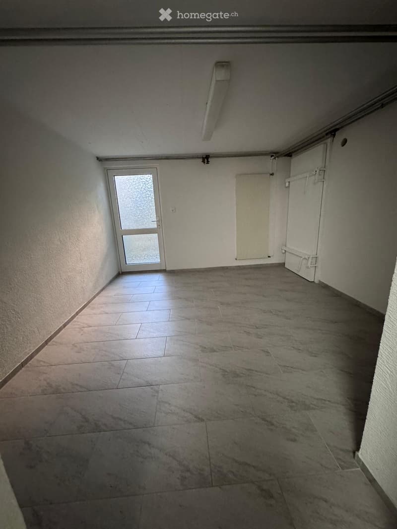 Empty room with tiled floor and white walls, featuring a door with frosted glass panels and a closed cabinet.