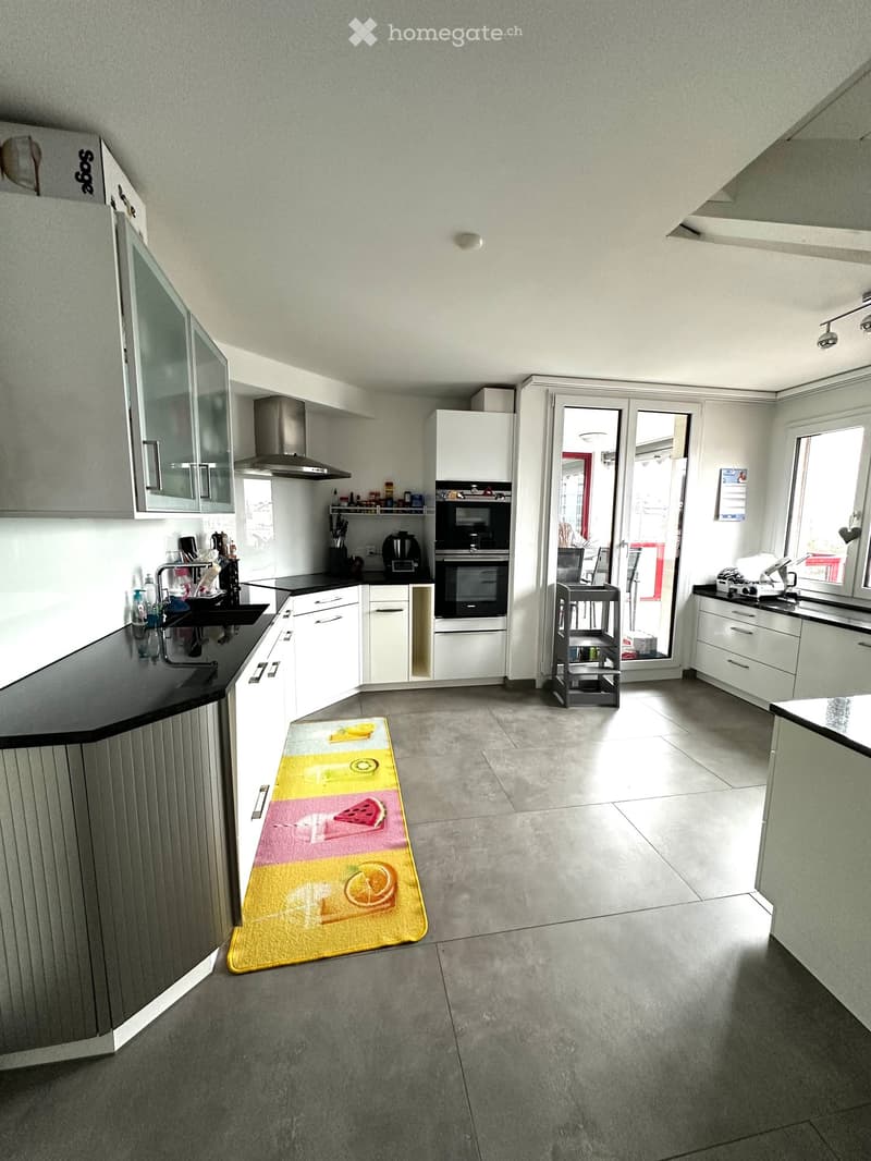 Modern kitchen with white cabinets, stainless steel appliances, and a black countertop. Features include a sink, oven, microwave, refrigerator, and various kitchen utensils.