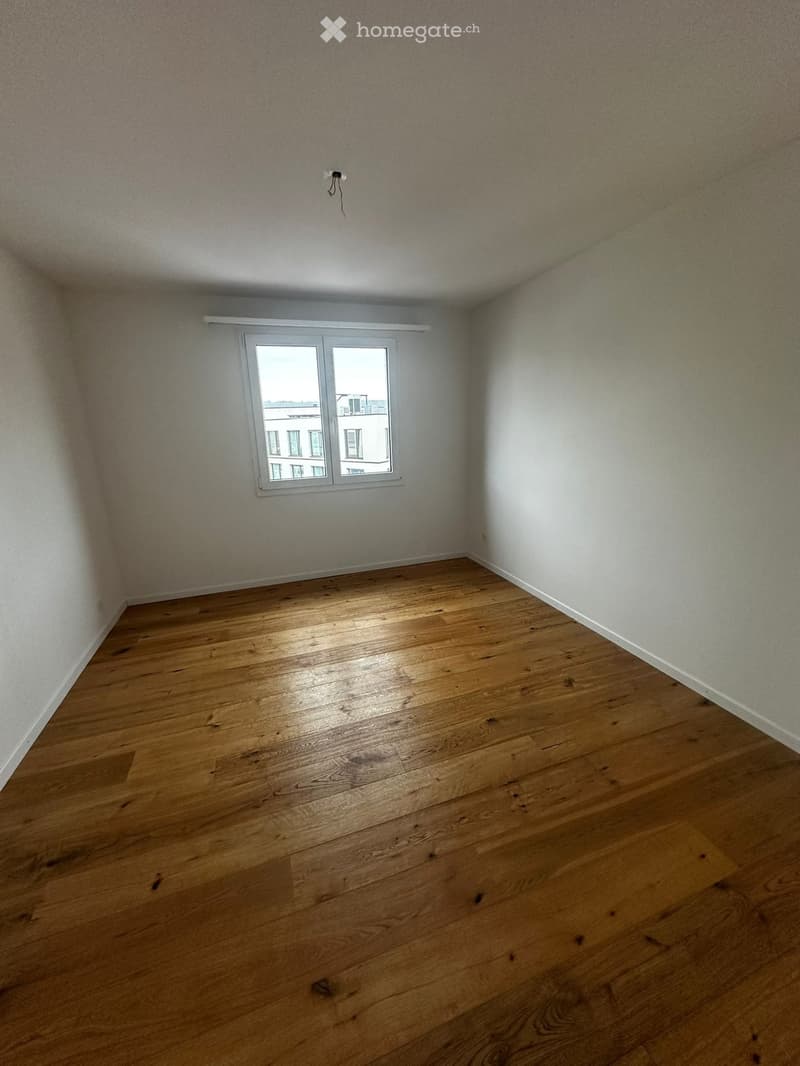Empty room with wooden flooring, white walls, and a single window with white frame.