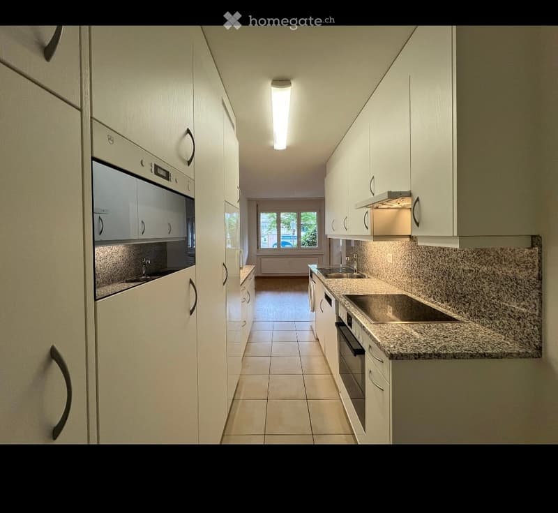 Modern kitchen with white cabinets, stainless steel appliances, granite countertop, and tiled floor.