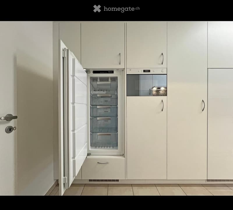 Modern kitchen with white cabinets, a stainless steel refrigerator, and a built-in oven.